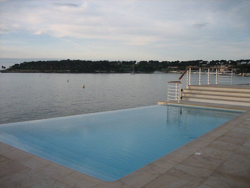 lookin gout over an infinity pool to a large body of water beyond it