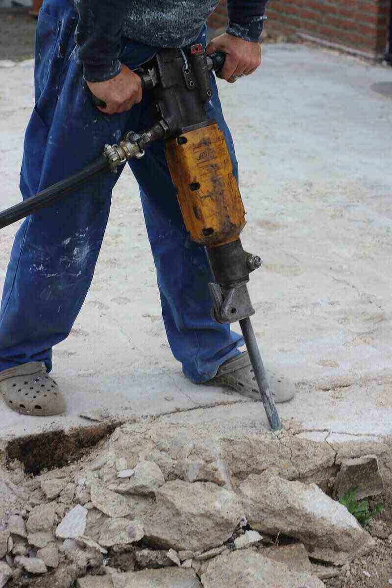 Worker using a hammer drill to break up concrete