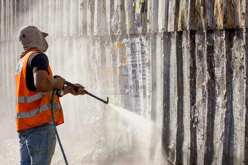 Worker using a pressure washer on a wall