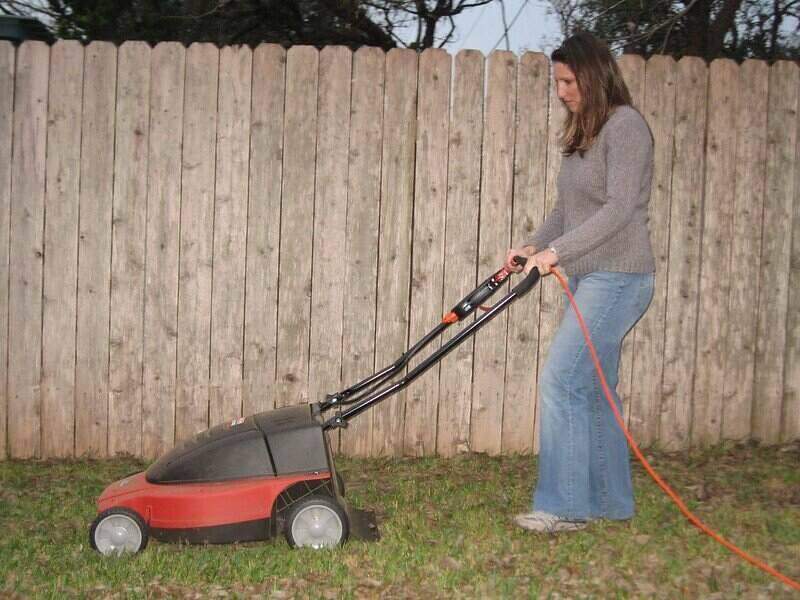 Woman using an electric lawn mower