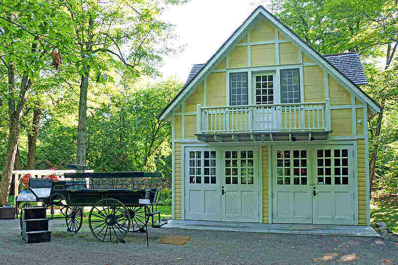 Yellow, two-car garage with an upstairs apartment and balcony