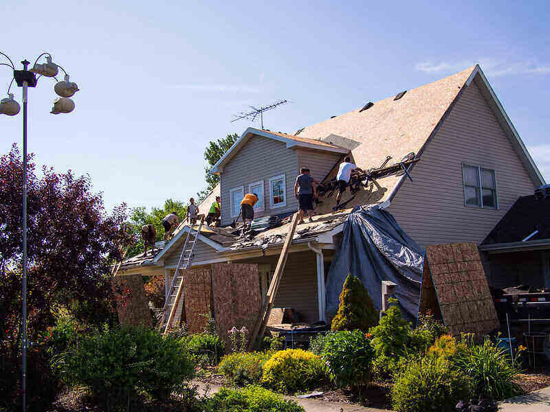 Workers providing a full roof replacement on a house