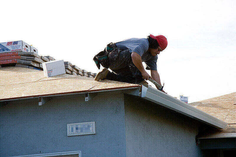Worker on the roof installing new gutters