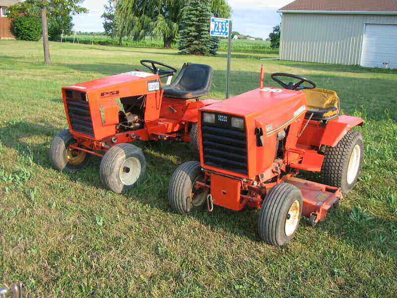 Two old lawn tractors sitting next to each other