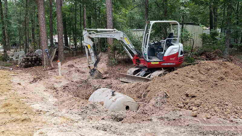 Backhoe burying a septic tank