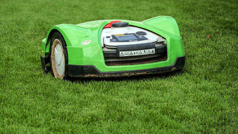 Green robot mower cutting a lawn
