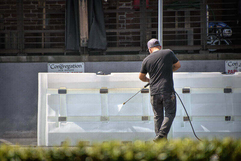 Man pressure washing a large item