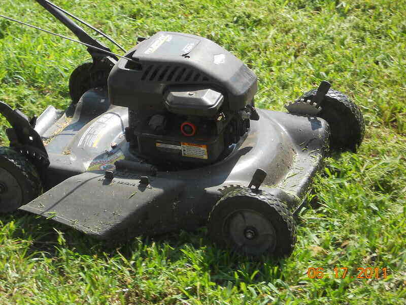 Close-up of a mulching lawn mower with grass clippings all over the top of it