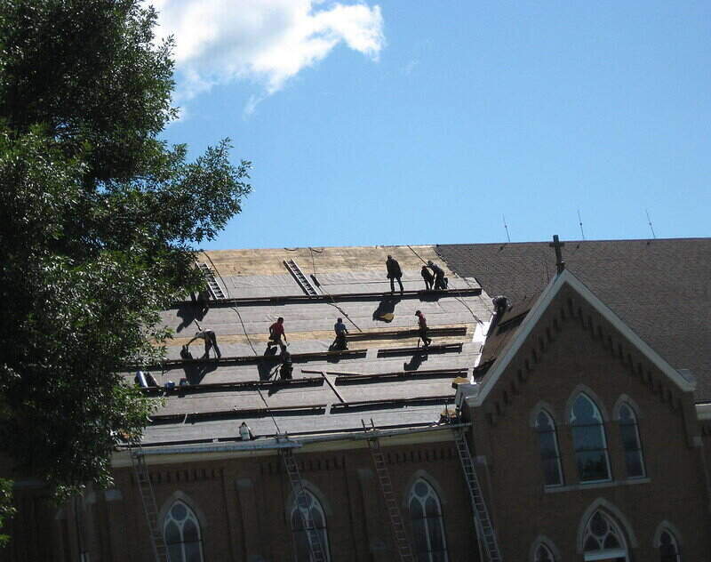 Roofers providing a roof replacement on a large roof