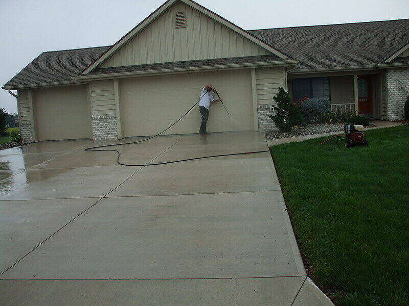 Man using a pressure washer on his driveway