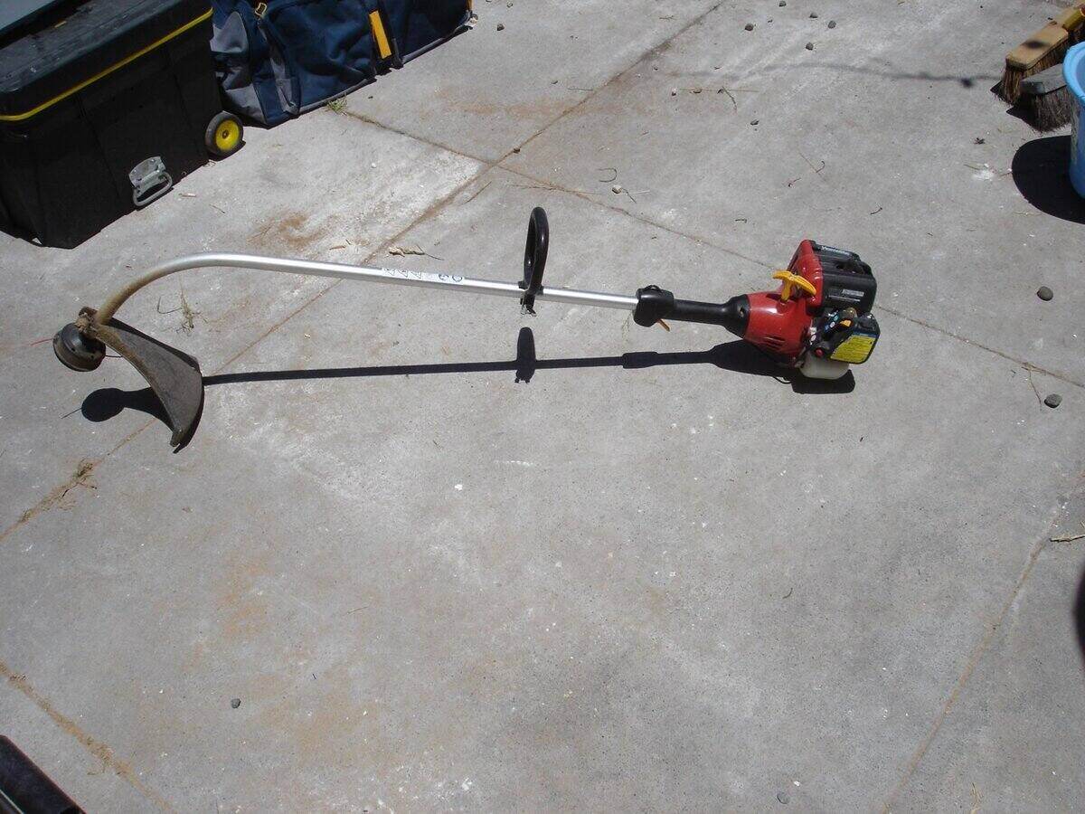 Gas string trimmer laying on the ground