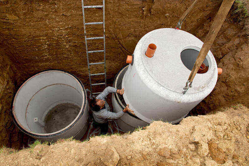 Septic tanks being lowered into a hole in various pieces