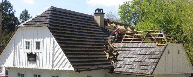 Worker removing wood tiles from a roof