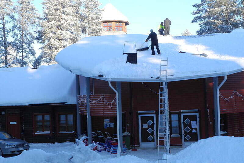 People removing snow from their roof using shovels