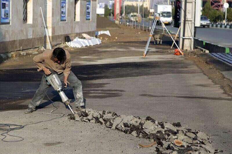 Worker using a hammer drill to break up concrete