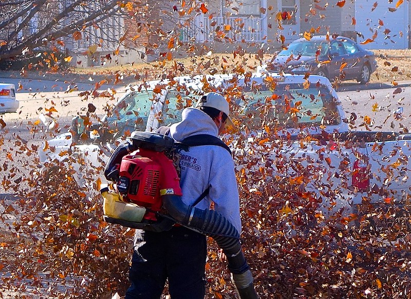 man blowing leaves off driveway with gas powered leaf blower