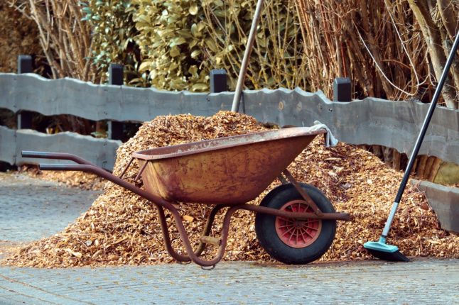 wheelbarrow and rake sitting beside pile of mulch