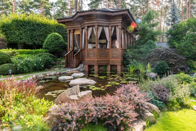 brown wooden gazebo overlooking pond and landscaping
