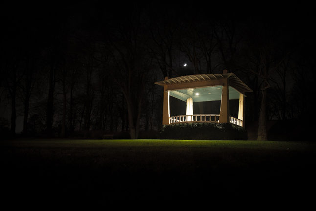 Gazebo lit up at night with woodland background