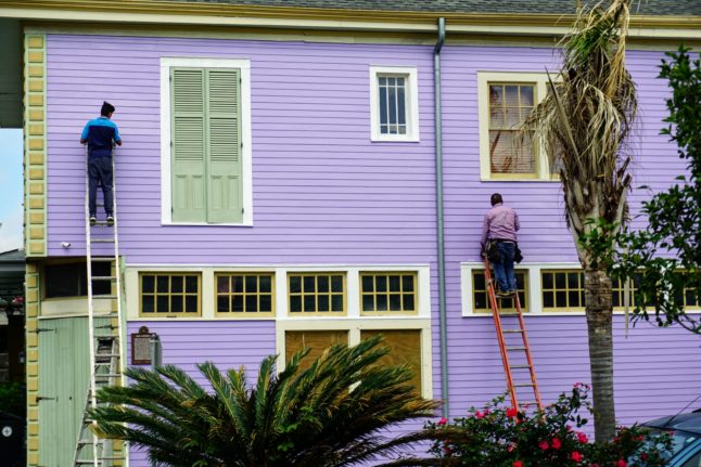 two men on ladders working on siding