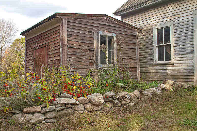 Wooden shed with landscaping a rocks bordering the area