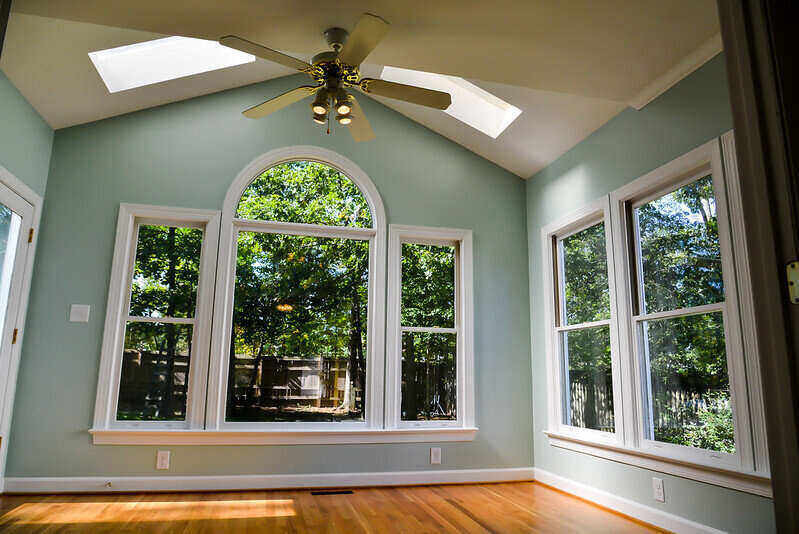 Newly painted and finished interior of a sunroom with large windows and skylights in the ceiling