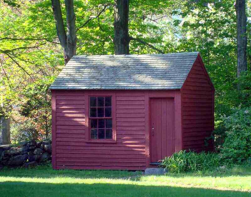 Maroon painted wooden shed set at the edge of the woods