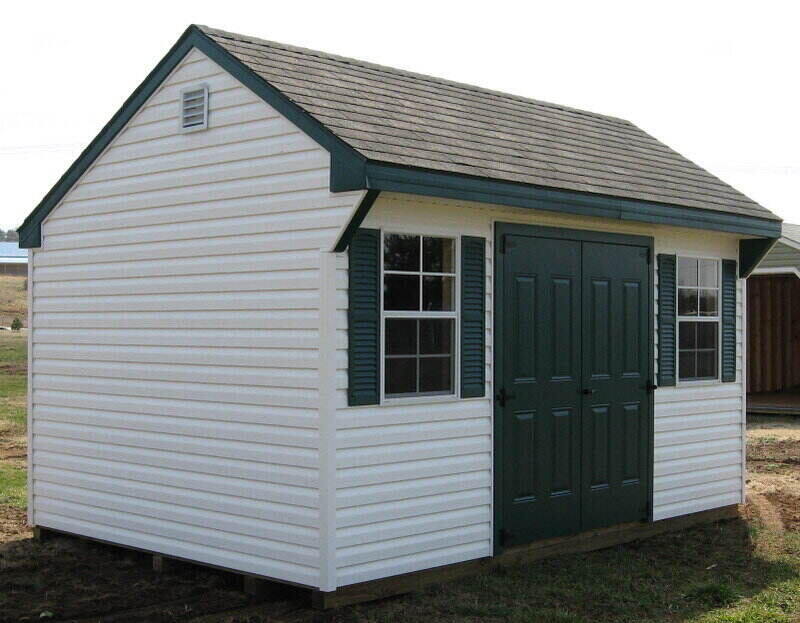 White prefabricated shed with vinyl siding and painted doors and shutters.