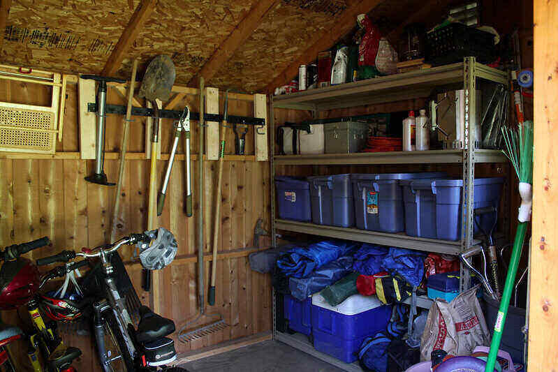 Newly build shed with organized shelving and hooks for garden tools