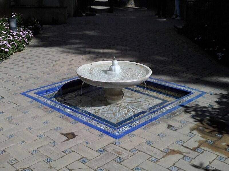 Ornate outdoor water fountain with blue and white decorative tile surrounding the base