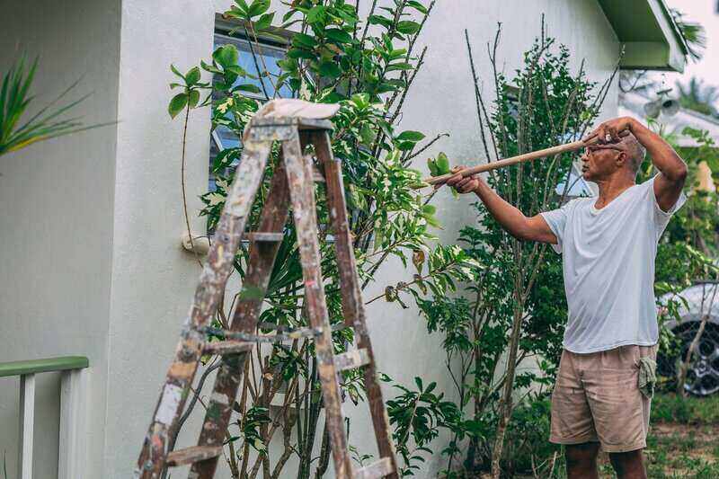 Man using a roller to paint the exterior of his house