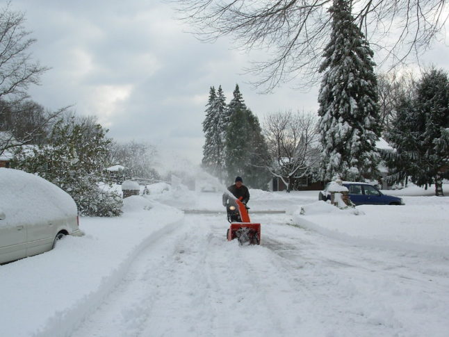man clearing snow with snowblower off driveway