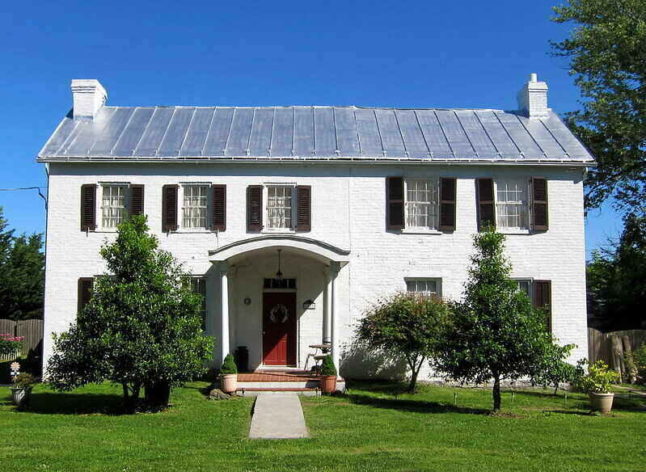 standing seam metal roof on top of historic white brick house