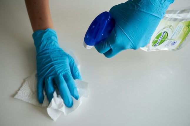 gloved hands spraying surface with cleaner