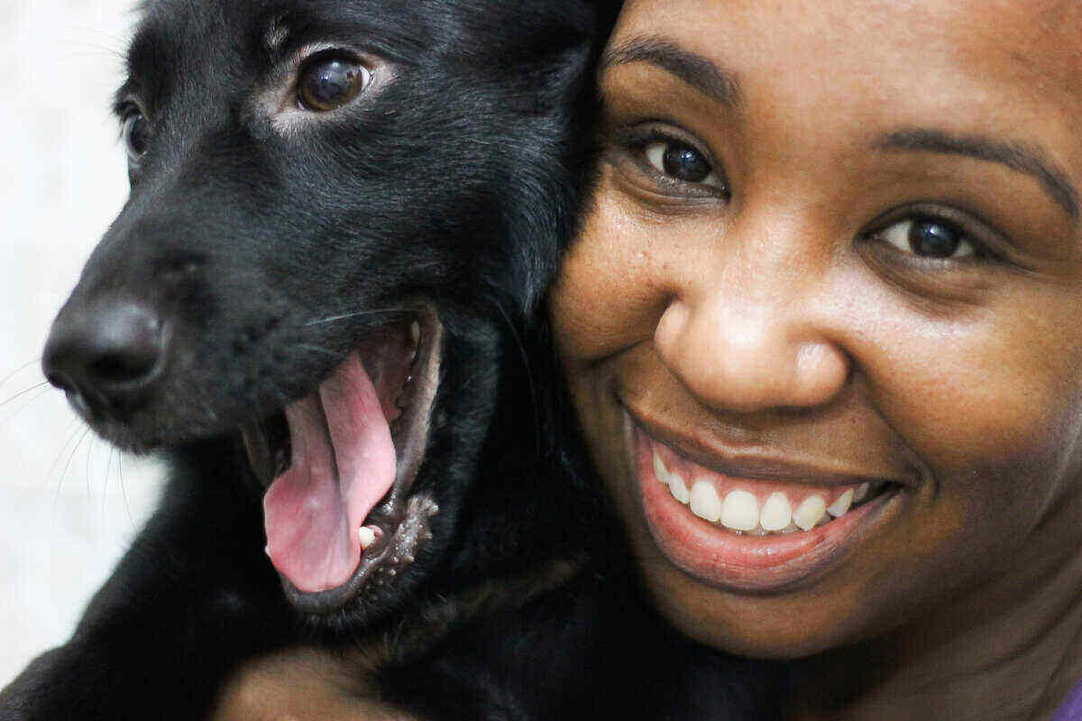 Closeup of African American woman holding black dog