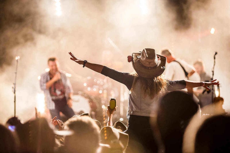 Woman in cowboy hat and crowd enjoying live country music show