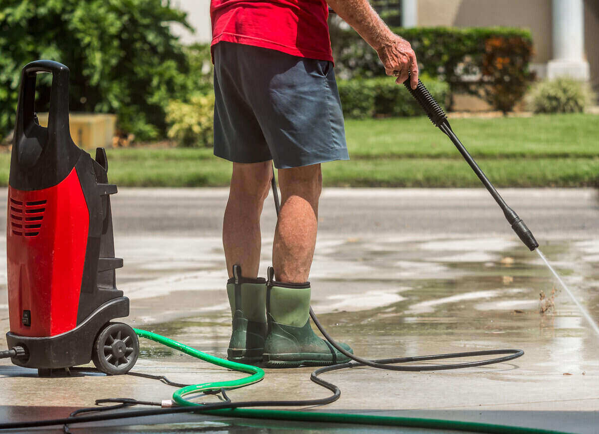Man using an electric pressure washer on concrete