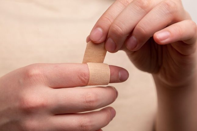 closeup of person wrapping bandaid around index finger