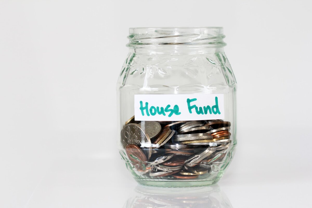 clear jar with a tag reading "House Fund", with coins inside