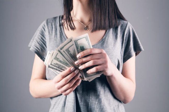 woman holding a stack of fanned out $100 bills