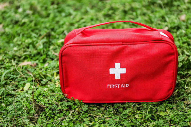 Red first aid kit sitting on a field of grass