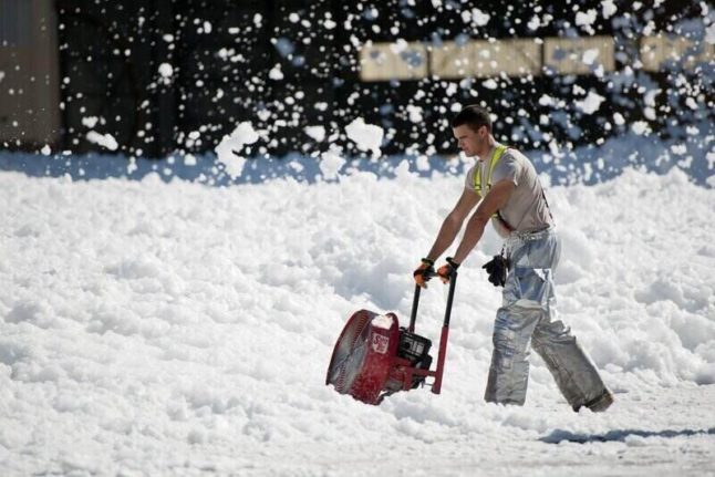 A man pushes a snow thrower, aka snow blower, to move a mound of snow.