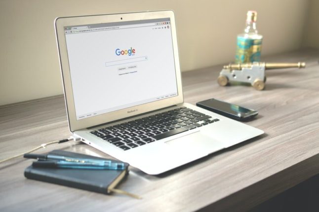 grey macbook air displaying google sitting on wooden desk