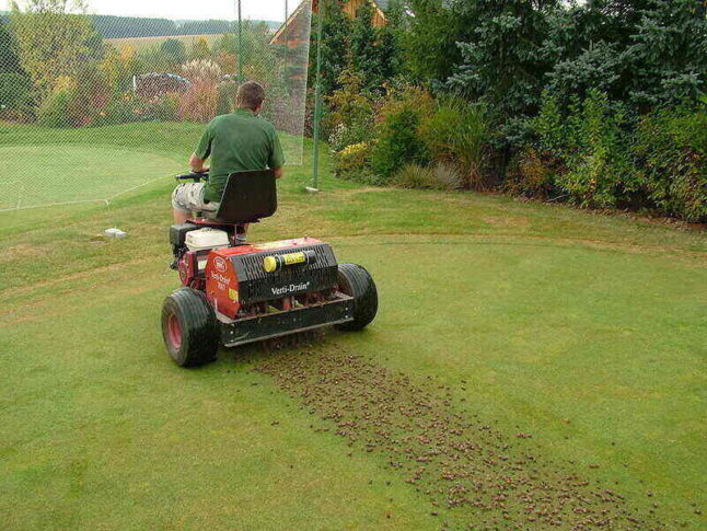 Man aerating grass using a riding automatic aerator