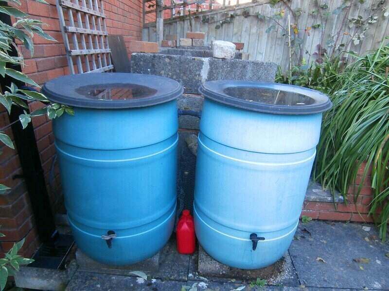 two blue rain barrels next to a house