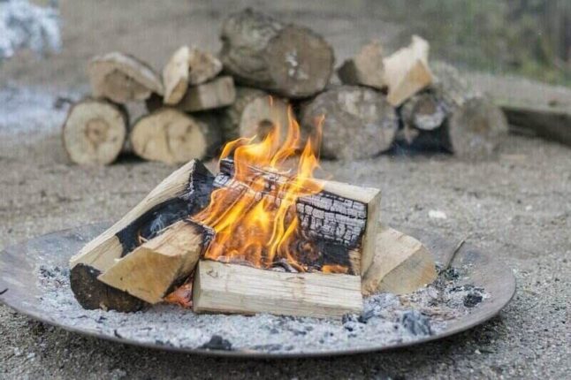 Fire pit on what looks like a metal bowl with wood burning on top