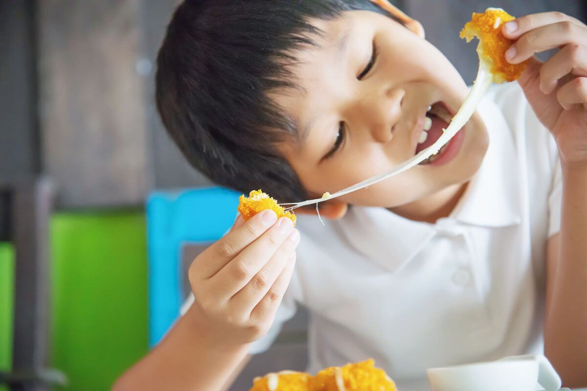 Boy splitting a cheese ball to enjoy the stringy cheese in the center