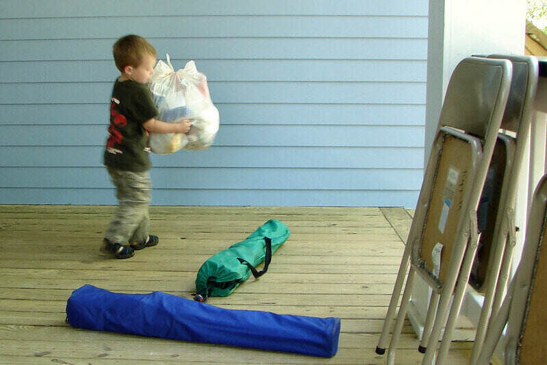 young boy carrying a large trash bag for removal