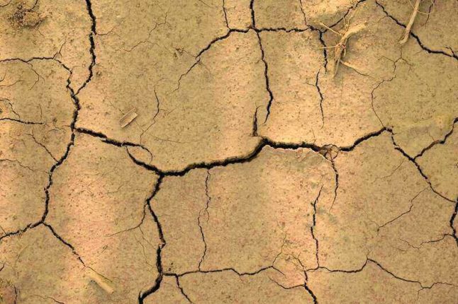 Cracked tan-colored clay earth, drought up close