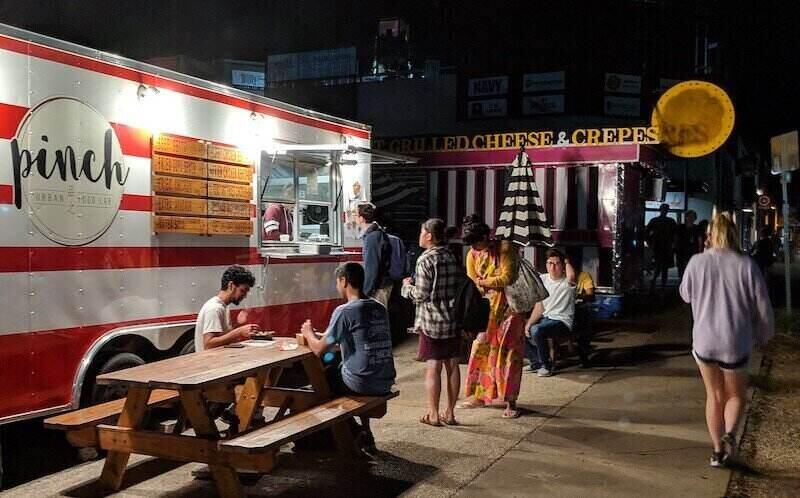 Image of patrons ordering from and eating at local food trucks near the University of Texas-Austin campus